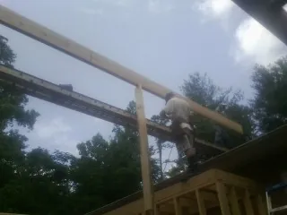 Carpenter setting a ridge beam over a new addition frame — Ice Dam Removal by Roofing Brothers in Brighton