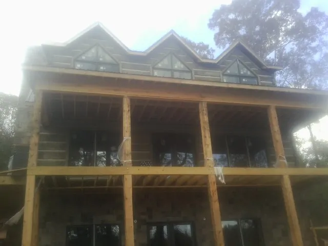 Dormers and porch framing on a large log home under construction — Roof Coating work by our crew in Brighton
